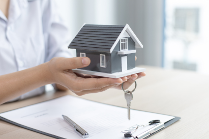 Hands holding a model house over paperwork