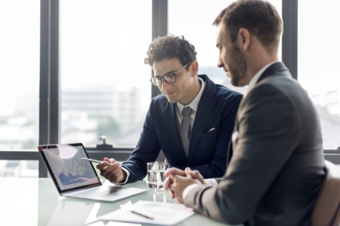 Two businessmen reviewing work at a laptop